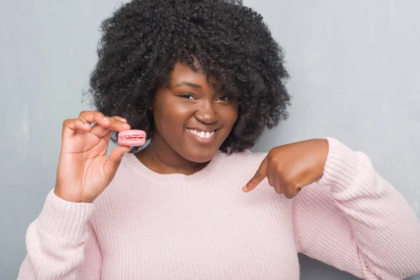 Jovem Afro Americana Sobre Parede Grunge Cinza Comendo Macaron Rosa — Fotografia de Stock