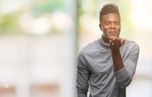 Молодий Афроамериканець Людиною Над Ізольованих Фону Дивлячись Дме Поцілунку Боку — стокове фото