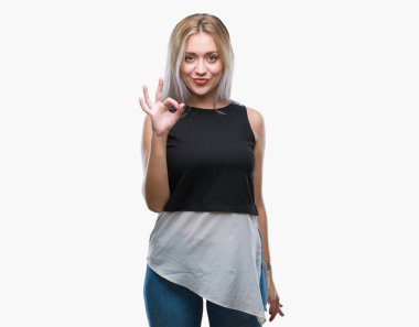 Gülümseyen izole arka plan üzerinde sarışın genç kadın el ve parmaklar ok işaretiyle yapıyor olumlu. Başarılı ifade.