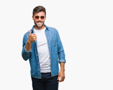 Genç yakışıklı adam hareketi el ile mutlu yaşasın yapıyor izole arka plan üzerinde güneş gözlüğü takıyor. Kameraya bakarak başarı gösteren ile ifade onaylama.