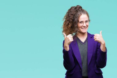 Okul üniforması ve gözlük el ile pozitif jest yapıyor izole arka plan başarı işareti üzerinde giyen genç esmer öğrenci kız gülümseyerek ve mutlu yaşasın. Neşeli bir ifadeyle, kazanan jest kameraya bakıyor.