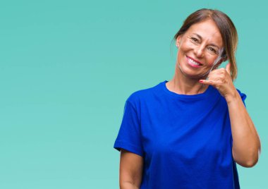 Orta yaş yapıyor gülümseyen izole arka plan üzerine İspanyol kadın kıdemli telefon hareketi ile el ve parmak telefonda konuşuyor gibi. Kavramları iletişim.