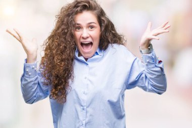 Güzel esmer kıvırcık saçlı Genç kız giyen elgant deli kutluyor izole arka plan üzerinde bakmak ve çığlık kaldırdı ve açık gözleri heyecanlı silah ile başarı için hayrete düşürdü. Kazanan kavramı