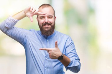 Genç beyaz hipster adam elleriyle yapım çerçeve ve parmakları ile mutlu yüz gülümseyen izole arka plan üzerinde. Yaratıcılık ve Fotoğrafçılık kavramı.