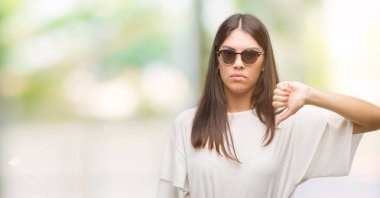 Başparmak aşağı, ret kavramı ile eksi işareti gösteren genç güzel İspanyol kızgın yüzü ile güneş gözlüğü takıyor, sevmemek