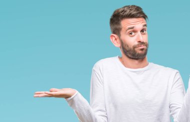 İzole arka plan clueless ve şaşkın bir ifadeyle kollar ve eller kaldırdı genç yakışıklı adam. Şüphe kavramı.