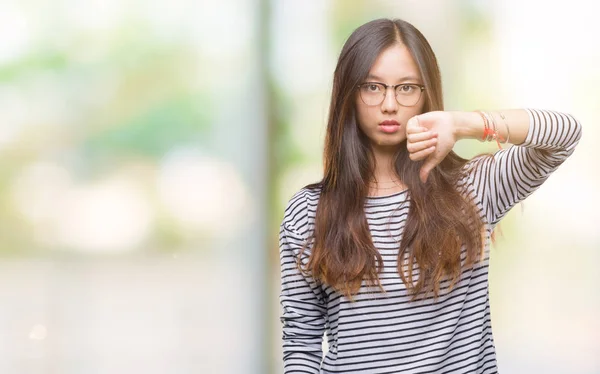 若いアジアの女性は 眼鏡を探して不幸と怒りの拒否反応を示さずジェスチャーを親指で否定的な分離の背景の上 不適切な表現 — ストック写真