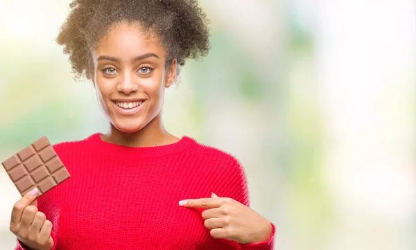 Junge Afroamerikanerin Isst Schokoriegel Über Isoliertem Hintergrund Mit Überraschendem Gesicht — Stockfoto