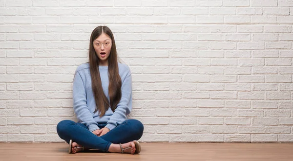 年轻的中国女子坐在地板上 墙上的砖墙吓了一惊 惊讶的表情 恐惧和兴奋的脸 — 图库照片