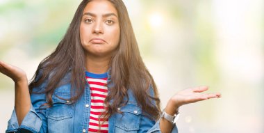 Genç güzel Arap kadın izole arka plan clueless ve şaşkın bir ifadeyle kollar ve eller kaldırdı. Şüphe kavramı.