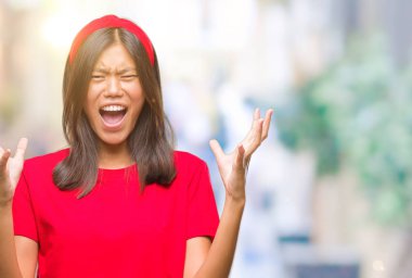 Genç Asyalı kadın izole arka plan çılgın ve kızgın bağırarak ve agresif ifade ve silah kaldırdı bağırıyor. Hayal kırıklığı kavramı.