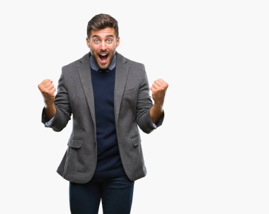 Genç yakışıklı iş adamı izole arka plan kutlama üzerinde şaşırttı ve başarı için kaldırdı kollarını açarak hayret ve gözleri açık. Kazanan kavramı.