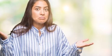 Genç güzel Arap kadın izole arka plan clueless ve şaşkın bir ifadeyle kollar ve eller kaldırdı. Şüphe kavramı.