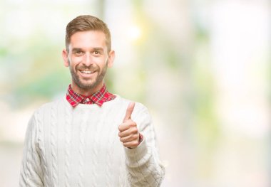 Hareketi el ile mutlu yaşasın yapıyor izole arka plan üzerinde kış kazak giyen genç yakışıklı adam. Kameraya bakarak başarı gösteren ile ifade onaylama.