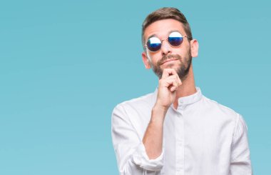 Çene düşünme hakkında soru, dalgın ifade üzerine el ile izole arka plan üzerinde gözlük takan yakışıklı delikanlı. Düşünceli yüzüyle gülümsüyor. Şüphe kavramı.