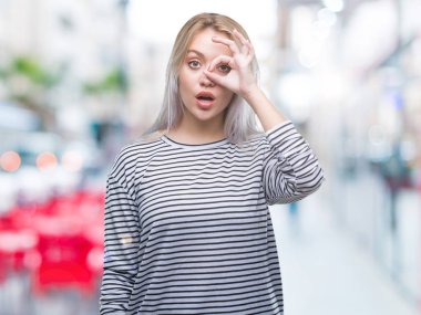 Sürpriz yüz, göz parmaklarının arasından seyir ile ok jest yapıyor izole arka plan üzerinde sarışın genç kadın şok. İmansız ifade.