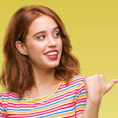 Seyir ve başparmak yanında yukarıyı mutlu yüz ile gülümseyen izole arka plan üzerinde genç güzel kadın.