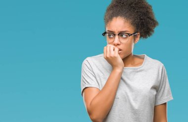 Stresli ve gergin elle çivi ısırma ağzına bakarak izole arka plan üzerinde gözlük takan genç afro Amerikalı kadın. Anksiyete sorunu.