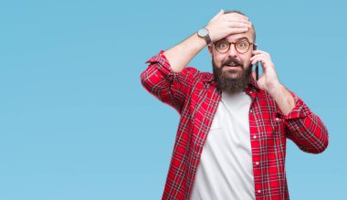 Smartphone kafa üzerinde el ile vurguladı izole arka plan üzerinde konuşan genç beyaz hipster adam şok utanç ve sürpriz suratla, öfkeli ve sinirli. Korku ve hata için üzgün.