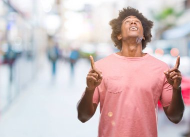 Afro Amerikalı adam izole arka plan üzerinden hayran ve yukarıya bakıp parmakları ile işaret şaşırttı ve silah kaldırdı.