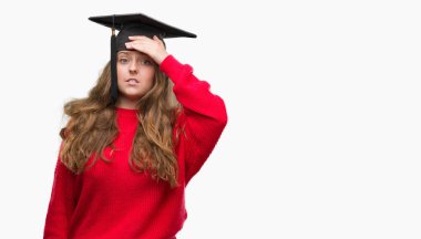 Baş, el ile vurguladı mezuniyet şapkası sarışın genç kadın şok utanç ve sürpriz suratla, öfkeli ve sinirli. Korku ve hata için üzgün.