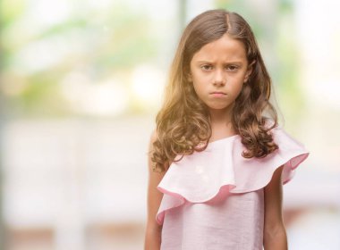 Esmer Latin kız pembe elbise şüpheci ve sinir, papatyanın üzgün sorunu nedeniyle giyiyor. Negatif kişi.