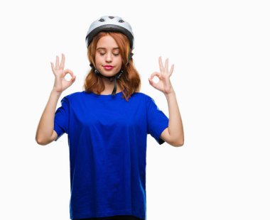 Genç güzel kadın giyiyor bisikletçi kask izole arka plan üzerinde dinlenmek ve gülümseyen gözlerle kapalı parmak jestle meditasyon yapıyor. Yoga kavramı.