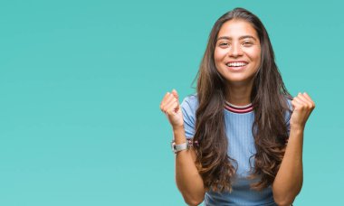 Genç güzel Arap kadın kutluyor izole arka plan üzerinde şaşırttı ve başarı için kaldırdı kollarını açarak hayret ve gözleri açık. Kazanan kavramı.