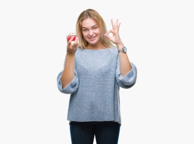 Parmak, mükemmel sembolü ile ok işareti yapıyor izole arka plan üzerinde tatlı kek yeme genç kafkas kadın