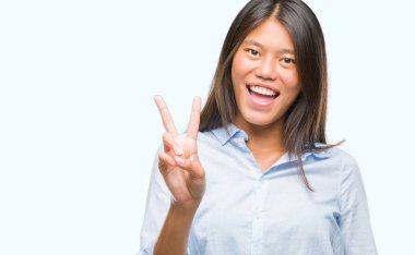 Genç Asyalı iş kadını mutlu yüz zafer işareti yaparken kameraya göz kırpıyor ile gülümseyen izole arka plan üzerinde. İki numaralı.