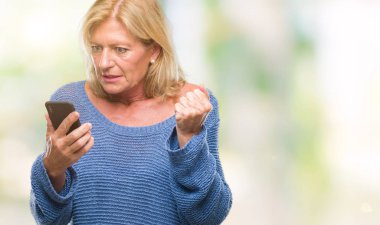 Orta yaş sarışın kadın öfkeyle, çılgın ve bağrışmalar yükseltilmiş el, öfke kavramı ile smartphone üzerinde izole arka rahatsız ve sinirli bağırarak kullanarak ileti gönderme