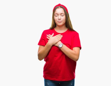 Göğüs kapalı gözler ve yüzünde minnettar jest ile güzel bir beyaz genç kadın ile gülümseyen izole arka plan üzerinde eller. Sağlık kavramı.