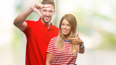 Genç çift elle yapma çerçeve ve parmakları ile mutlu yüz gülümseyen izole arka plan üzerinde aşık. Yaratıcılık ve Fotoğrafçılık kavramı.