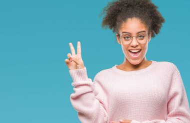 Mutlu yüz zafer işareti yaparken kameraya göz kırpıyor ile gülümseyen izole arka plan üzerinde gözlük takan genç afro Amerikalı kadın. İki numaralı.