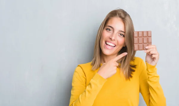 Schöne Junge Frau Über Grunge Graue Wand Essen Schokoladenriegel Sehr — Stockfoto