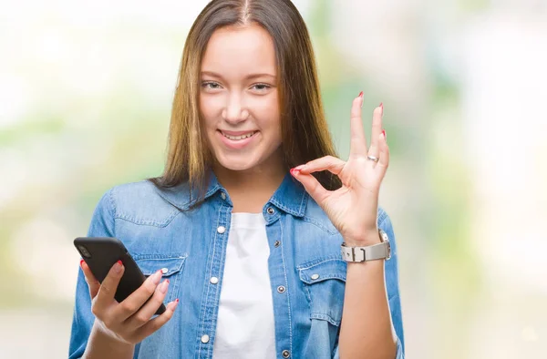 年轻美丽的白人妇女短信发送消息使用智能手机在孤立的背景做 符号与手指 优秀的符号 — 图库照片