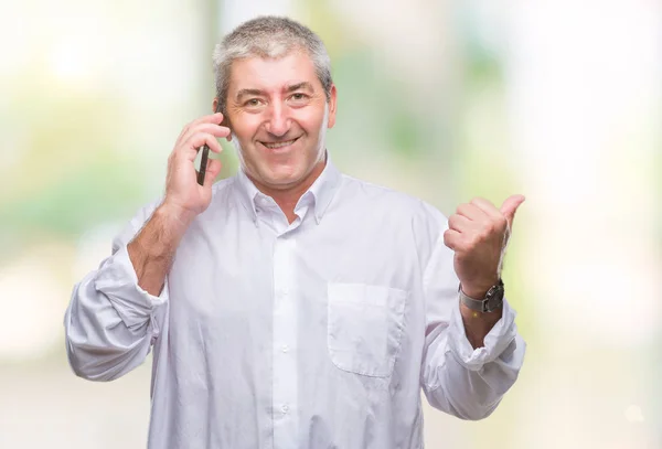Handsome senior man talking on smartphone over isolated background pointing and showing with thumb up to the side with happy face smiling