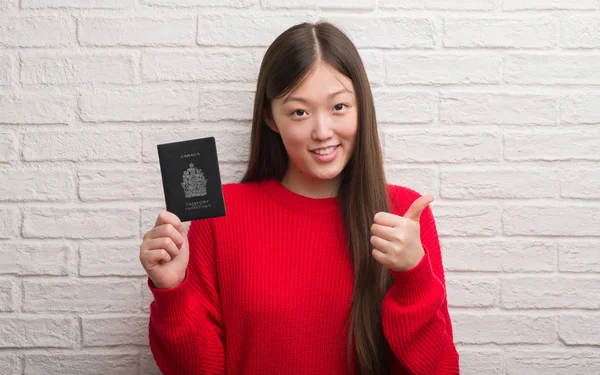 Joven Mujer China Sobre Pared Ladrillo Con Pasaporte Canadá Feliz —  Fotos de Stock