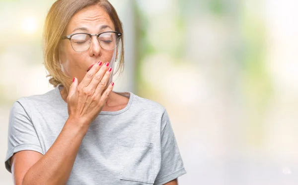 中年资深西班牙裔妇女戴着眼镜在孤立的背景下无聊的打呵欠 用手捂住嘴巴 不安和嗜睡 — 图库照片