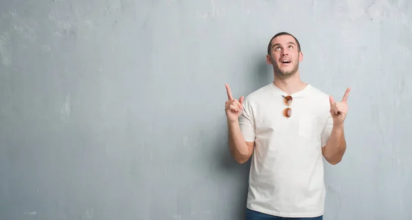 Joven Hombre Caucásico Sobre Pared Grunge Gris Con Gafas Sol —  Fotos de Stock