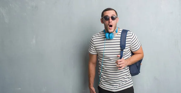 Joven Estudiante Caucásico Sobre Pared Grunge Gris Usando Auriculares Mochila —  Fotos de Stock