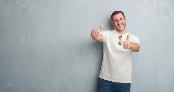 Joven Hombre Caucásico Sobre Pared Gris Grunge Usando Gafas Sol — Foto de Stock