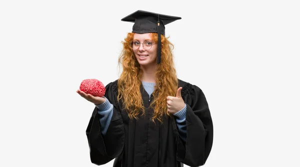 Giovane Studentessa Rossa Con Indosso Uniforme Graduata Che Tiene Cervello — Foto Stock
