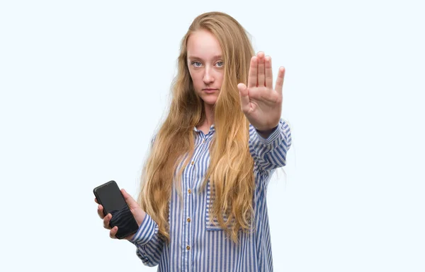 防衛ジェスチャー 深刻な自信を持って式に一時停止の標識を行うオープンの手でスマート フォンを使用して 代の金髪女性 — ストック写真
