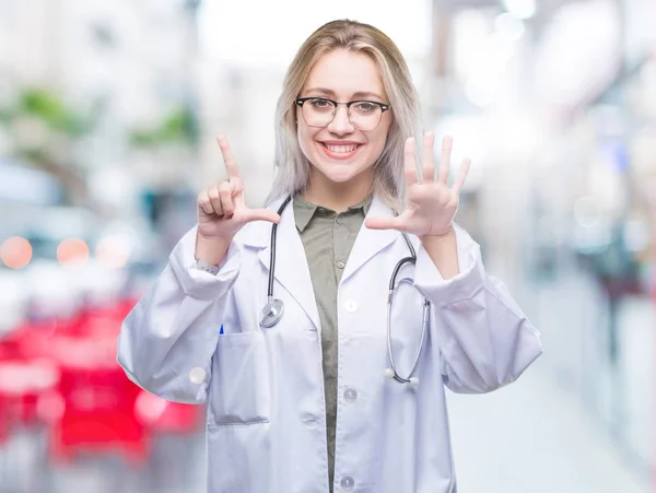 Young blonde doctor woman over isolated background showing and pointing up with fingers number seven while smiling confident and happy.