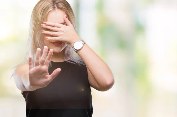 Young blonde woman over isolated background covering eyes with hands and doing stop gesture with sad and fear expression. Embarrassed and negative concept.