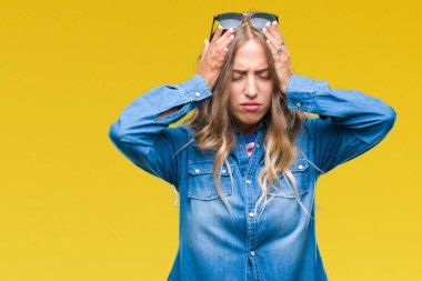 Çünkü çaresiz ve stresli baş ağrısı acı izole arka plan üzerinde güneş gözlüğü takıyor güzel sarışın genç kadın acı ve migren. Ellerini kafasına.