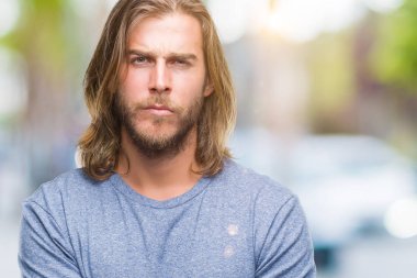 Yakışıklı delikanlı izole arka plan şüpheci ve sinir, onaylamayan ifade yüz çapraz kolları olan uzun saçlı. Negatif kişi.