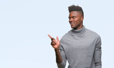 Kameraya bakarak yan el ve parmak ile işaret eden genç Afro-Amerikan adam yüzünde kocaman bir gülümseme ile izole arka plan üzerinde.