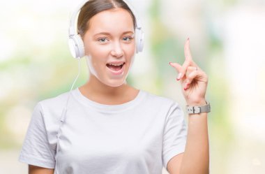 Genç kafkas kadın başarılı fikirle izole arka plan işaret parmağı üzerinde kulaklık giyen müzik dinlemek. Çıktıktan ve mutlu. Bir numara.